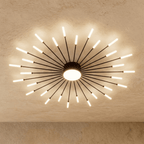 Clérachic starburst chandelier in black, a dense even ring, the frosted disc lighting the underside of the drum.