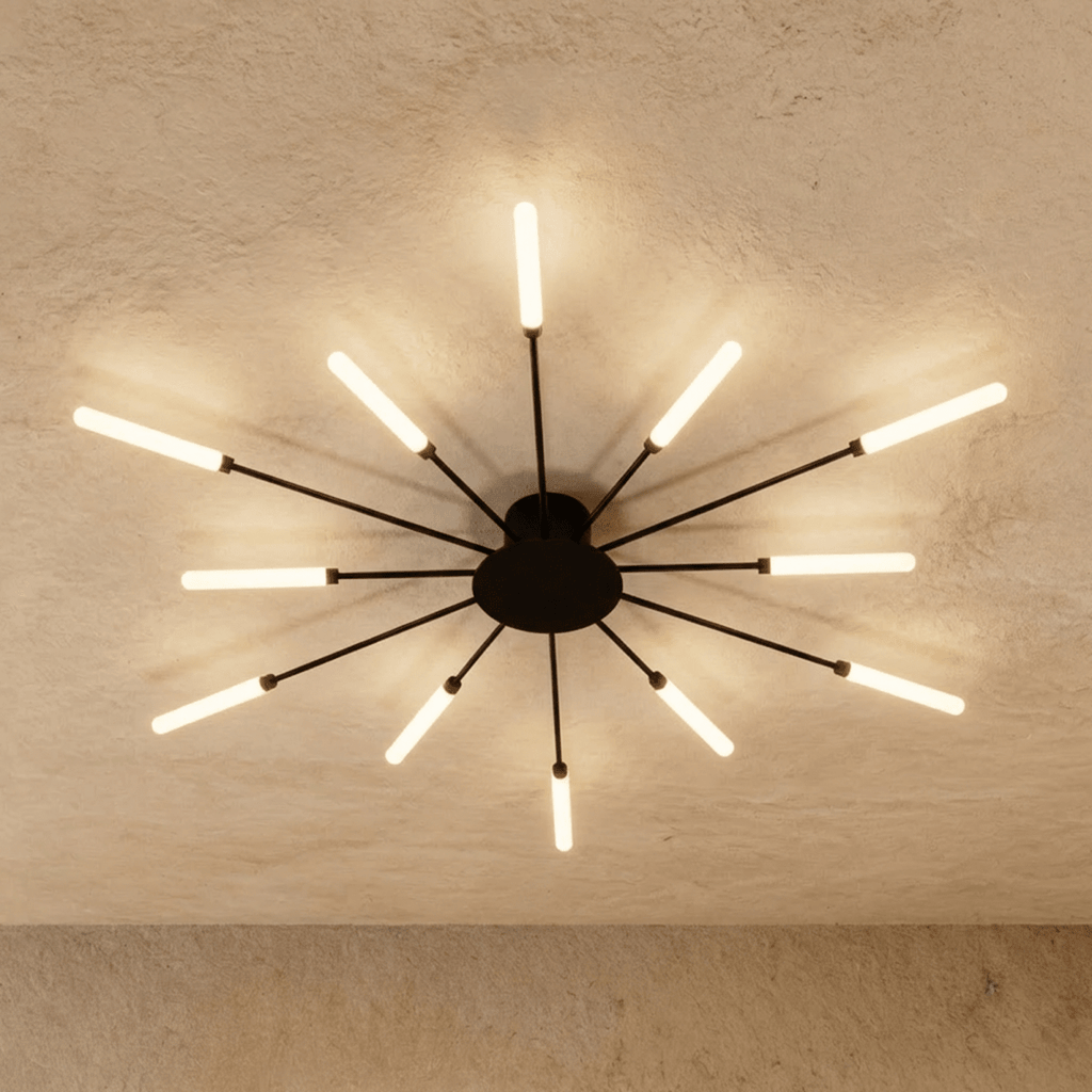 Clérachic starburst chandelier in black, twelve arms spaced evenly across a plain plaster ceiling, every tip lit.