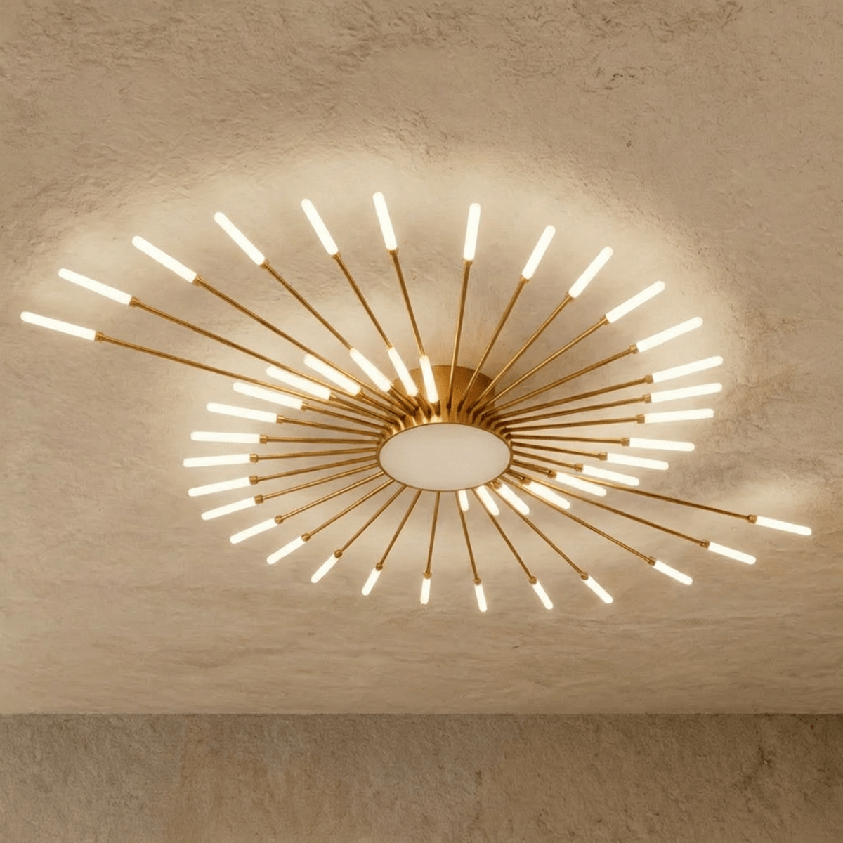 Clérachic starburst chandelier in gold, the same dense sweep, every rod converging on the drum above its lit disc.