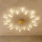 Clérachic starburst chandelier in gold, the same even ring, each rod capped by a plain collar before its frosted tube.