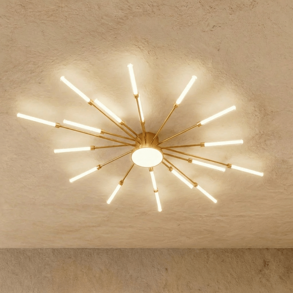Clérachic starburst chandelier in gold, the same evenly spaced arms, the frosted centre disc glowing white.