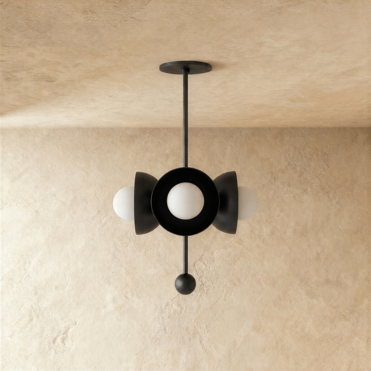 Clérachic disc-and-globe pendant light in matte black, shown from a slightly closer studio angle on a plaster wall.