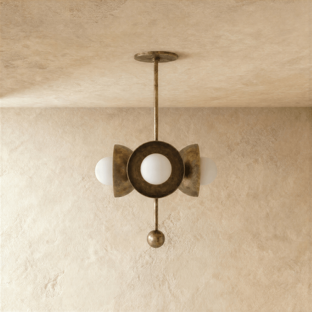 Clérachic disc-and-globe pendant light in vintage brass, shown from a slightly closer studio angle on a plaster wall.