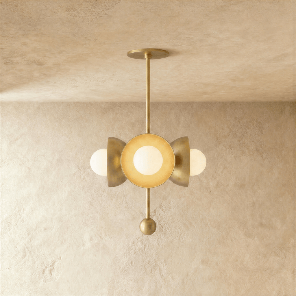 Clérachic disc-and-globe pendant light in polished brass, hung from a plaster ceiling and photographed in studio.