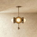 Clérachic disc-and-globe pendant light in vintage brass, hung from a plaster ceiling and photographed in studio.