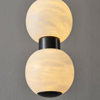 Extreme close-up of two lit alabaster spheres and the black metal collar that joins them
