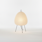 Rice paper table lamp on a slim tripod base, lit with a warm, even glow