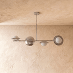 Clérachic pendant light in chrome, the asymmetric bar with glass globes shown from a slightly different angle.
