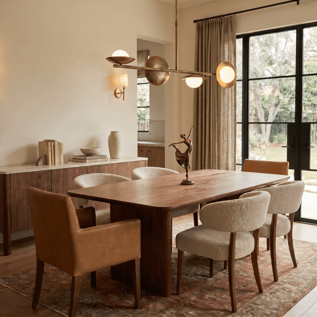 Clérachic vintage brass pendant light glowing above a wood dining table beside a gallery wall of framed art prints.