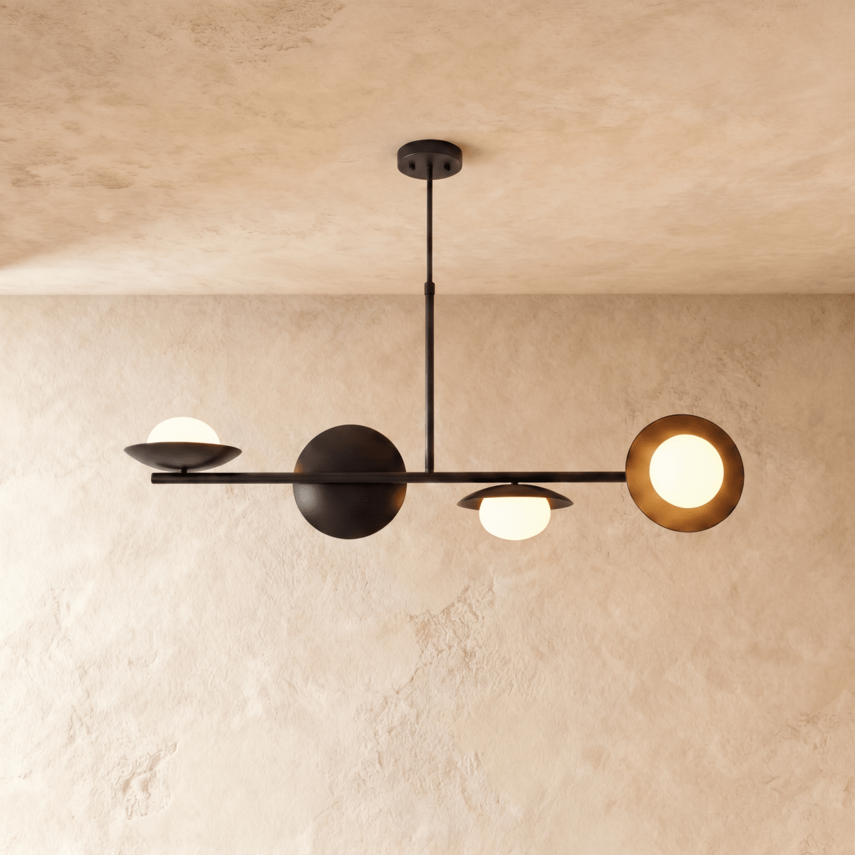 Clérachic pendant light in matte black, its sculptural spheres and opal glass globes lit against a plaster ceiling.