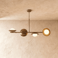 Clérachic pendant light in vintage brass, its sculptural spheres and opal glass globes lit against a plaster ceiling.
