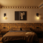 Clérachic marble globe wall lamps mounted as a matched pair either side of framed artwork, high on patterned wallpaper above a bed with ribbed brown bedding and a sheepskin.