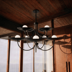 Clérachic matte black two-tier disc chandelier lit in a wood-panelled sunroom overlooking a mountain view.