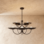 Clérachic two-tier disc chandelier in matte black with curved arms, hung from a plaster ceiling in studio light.