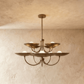 Clérachic two-tier disc chandelier in vintage brass with curved arms, hung from a plaster ceiling in studio light.