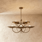 Clérachic two-tier disc chandelier in vintage brass with curved arms, hung from a plaster ceiling in studio light.