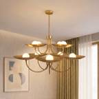 Clérachic brass two-tier disc chandelier lit above a living room with sheer curtains and abstract wall art.