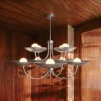 Clérachic chrome two-tier disc chandelier lit in a wood-panelled dining room beside a reeded glass door.
