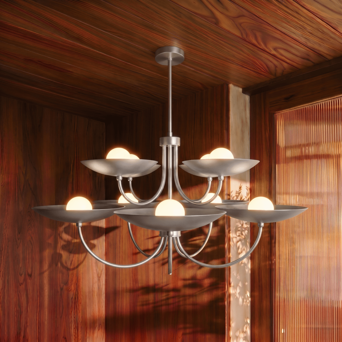 Clérachic chrome two-tier disc chandelier lit in a wood-panelled dining room beside a reeded glass door.