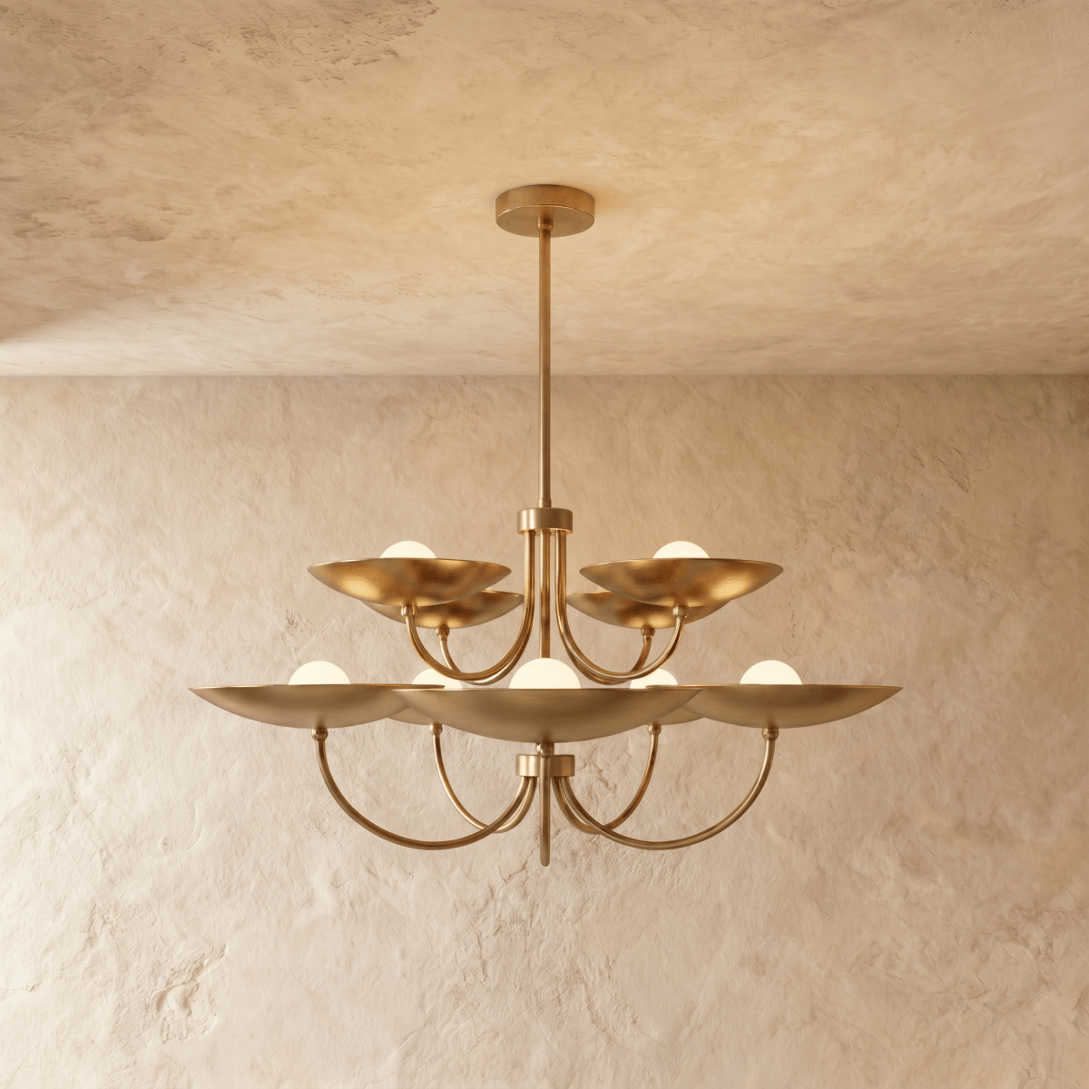 Clérachic two-tier disc chandelier in polished brass with curved arms, hung from a plaster ceiling in studio light.