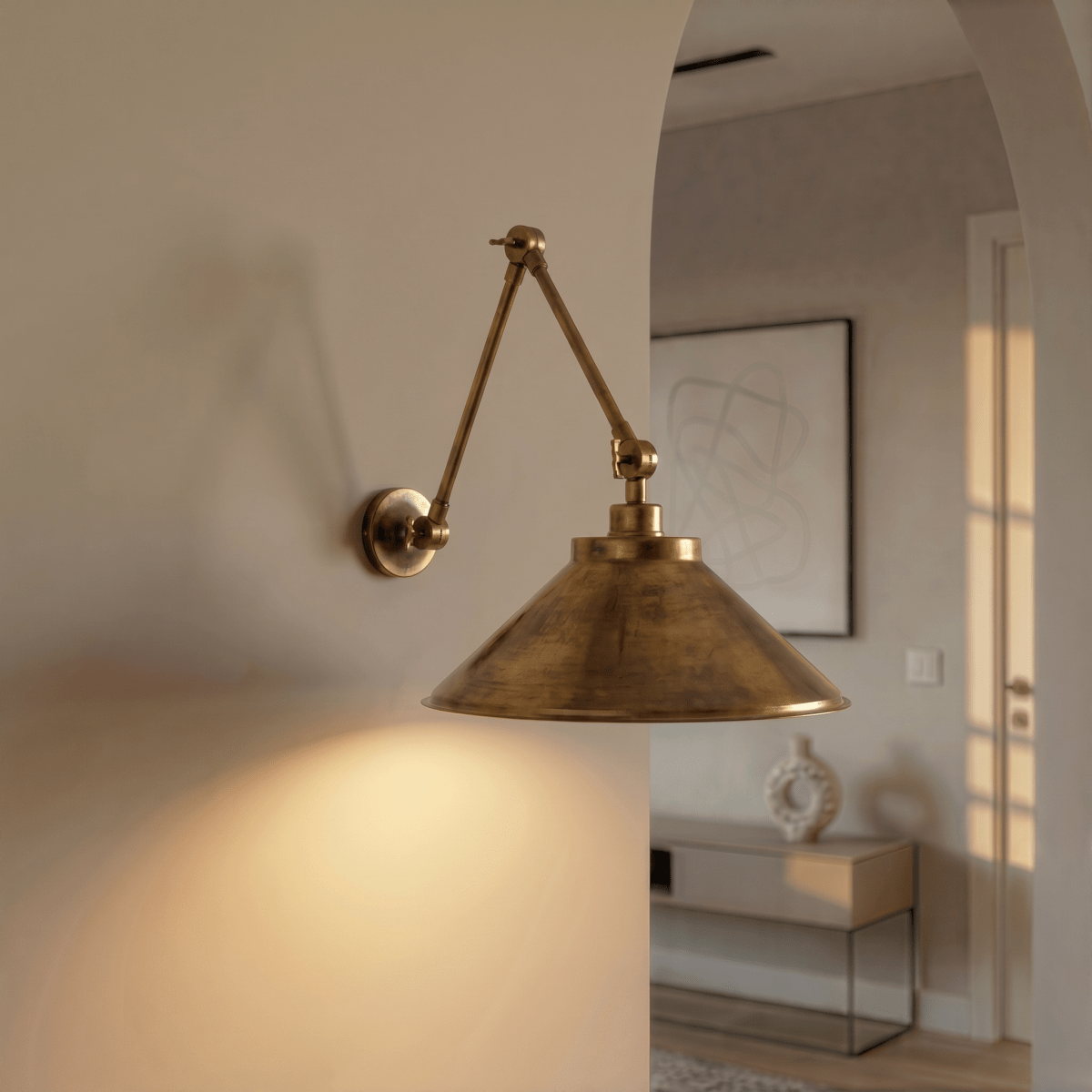 This vintage brass Clérachic wall lamp lights an archway leading to a console table and framed art.