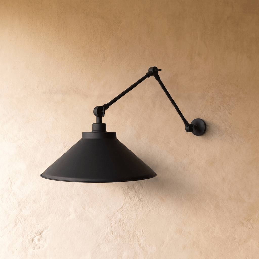 This black Clérachic wall lamp is shown from another angle, its cone shade tilted toward the light.