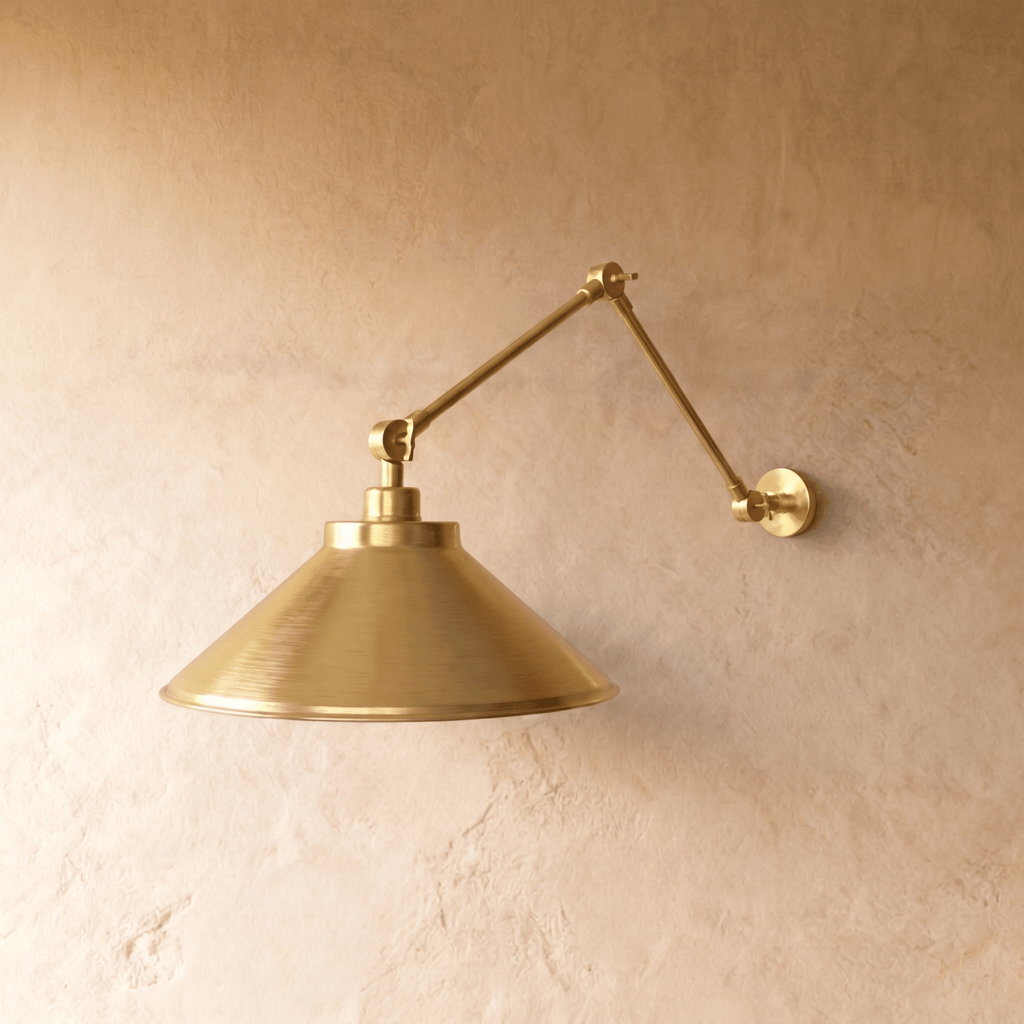This polished brass Clérachic wall lamp is shown from a different angle, the cone shade glowing warmly.
