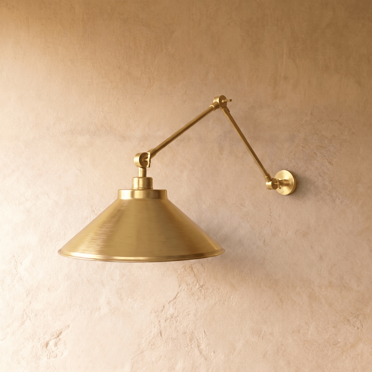 This polished brass Clérachic wall lamp is shown from a different angle, the cone shade glowing warmly.