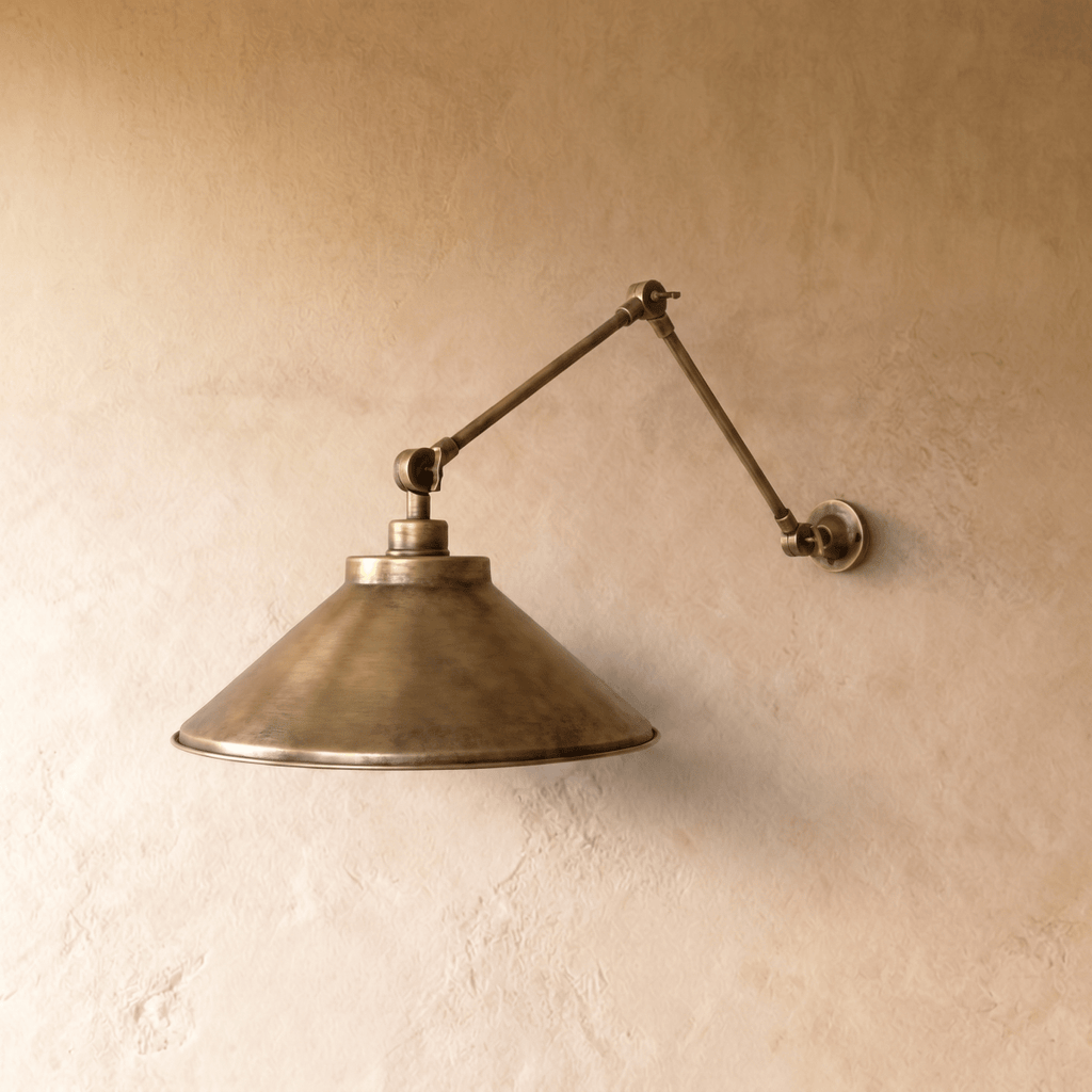 This vintage brass Clérachic wall lamp is shown from another angle, its cone shade tilted toward the light.