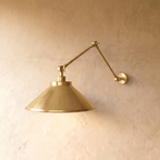Clérachic wall lamp in polished brass, its wide cone shade extending from a double-jointed arm.