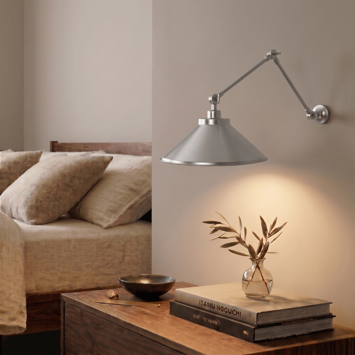 A chrome Clérachic wall lamp lights a walnut nightstand holding olive branches and stacked books.