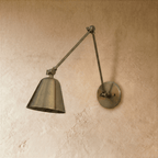 This Clérachic wall light in aged vintage brass shows the full swing-arm reach, shade tilted toward the floor.