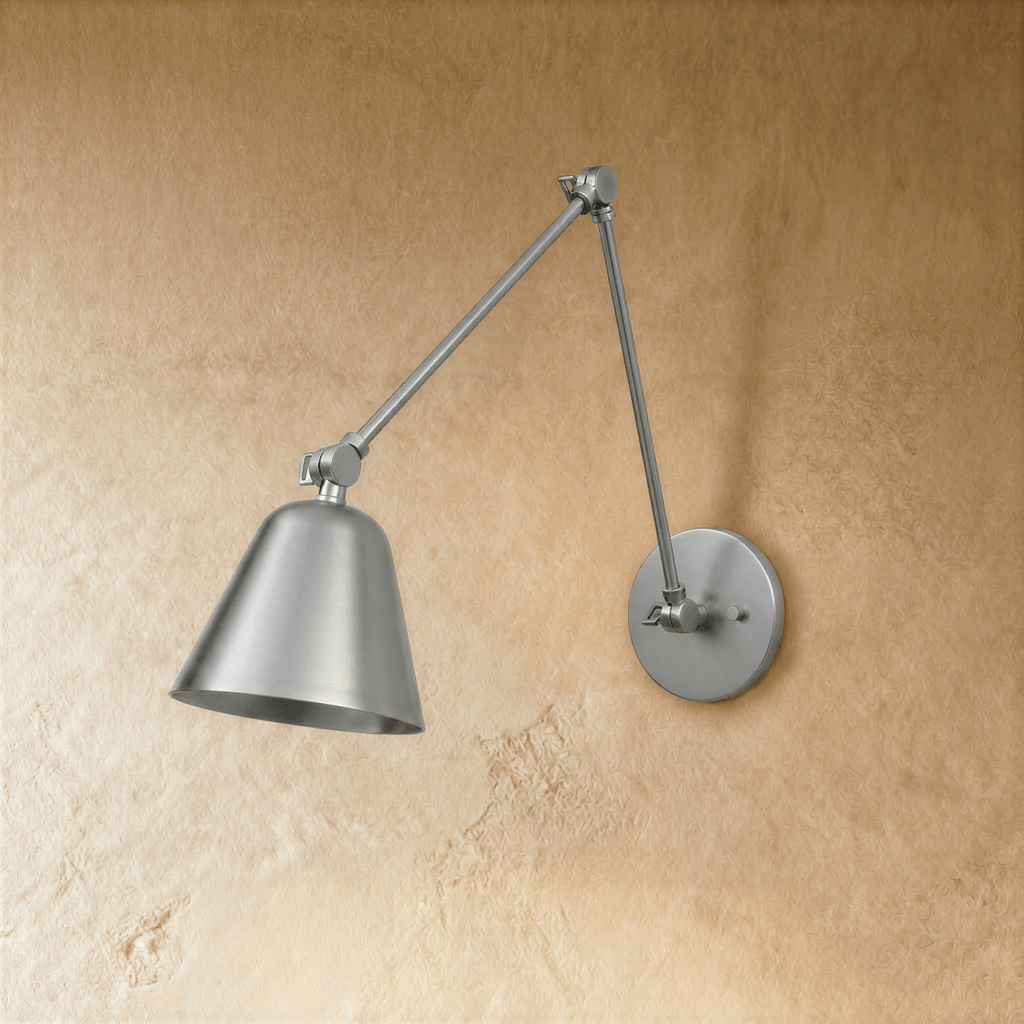 A Clérachic wall light in brushed chrome shows its jointed swing arm reaching left with the shade tilted down.