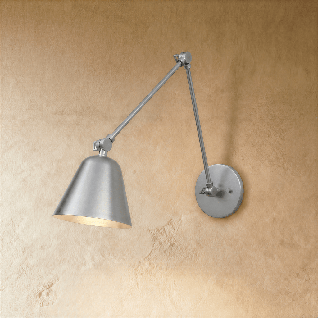This Clérachic swing-arm wall light in brushed chrome extends its arm with the cone shade angled downward.