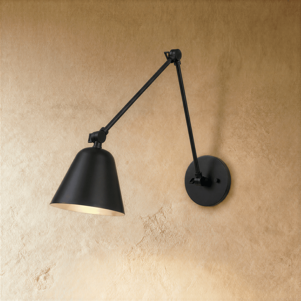 This Clérachic swing-arm wall light in matte black stands against a warm plaster wall, shade angled downward.