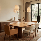 Clérachic brass chandelier hanging above a walnut dining table with a small bronze dancer figurine as a centrepiece.