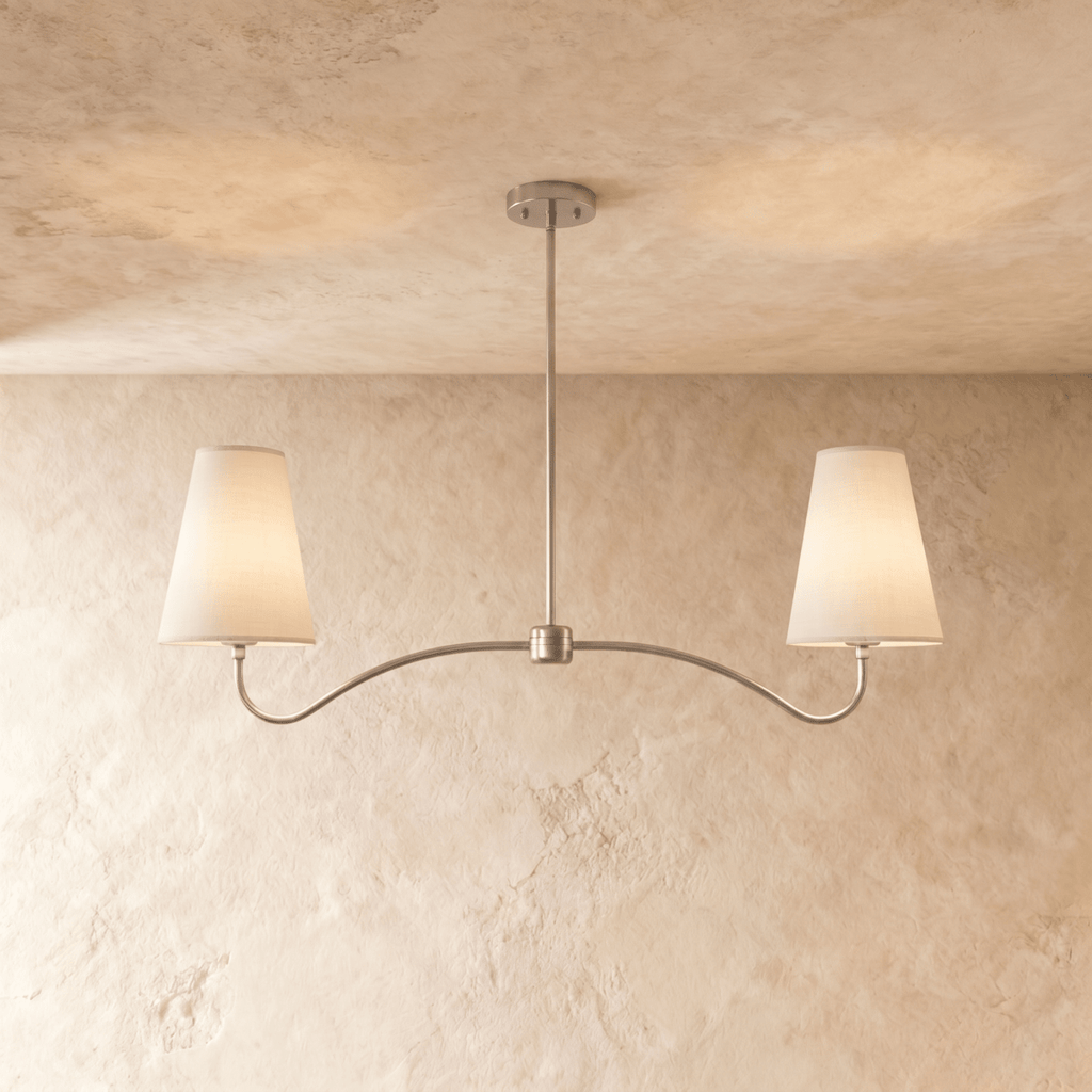 Clérachic double-arm chandelier in a bright chrome finish, its linen cone shades hung from a plaster ceiling.