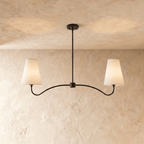 Clérachic double-arm chandelier in matte black, its linen cone shades hung from a plaster ceiling.