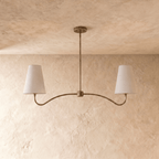 Clérachic double-arm chandelier in vintage brass, the curved arms and cone shades viewed from another angle.