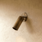 Clérachic wall lamp in vintage brass, close view of the tilted cylinder shade and oval wall plate.