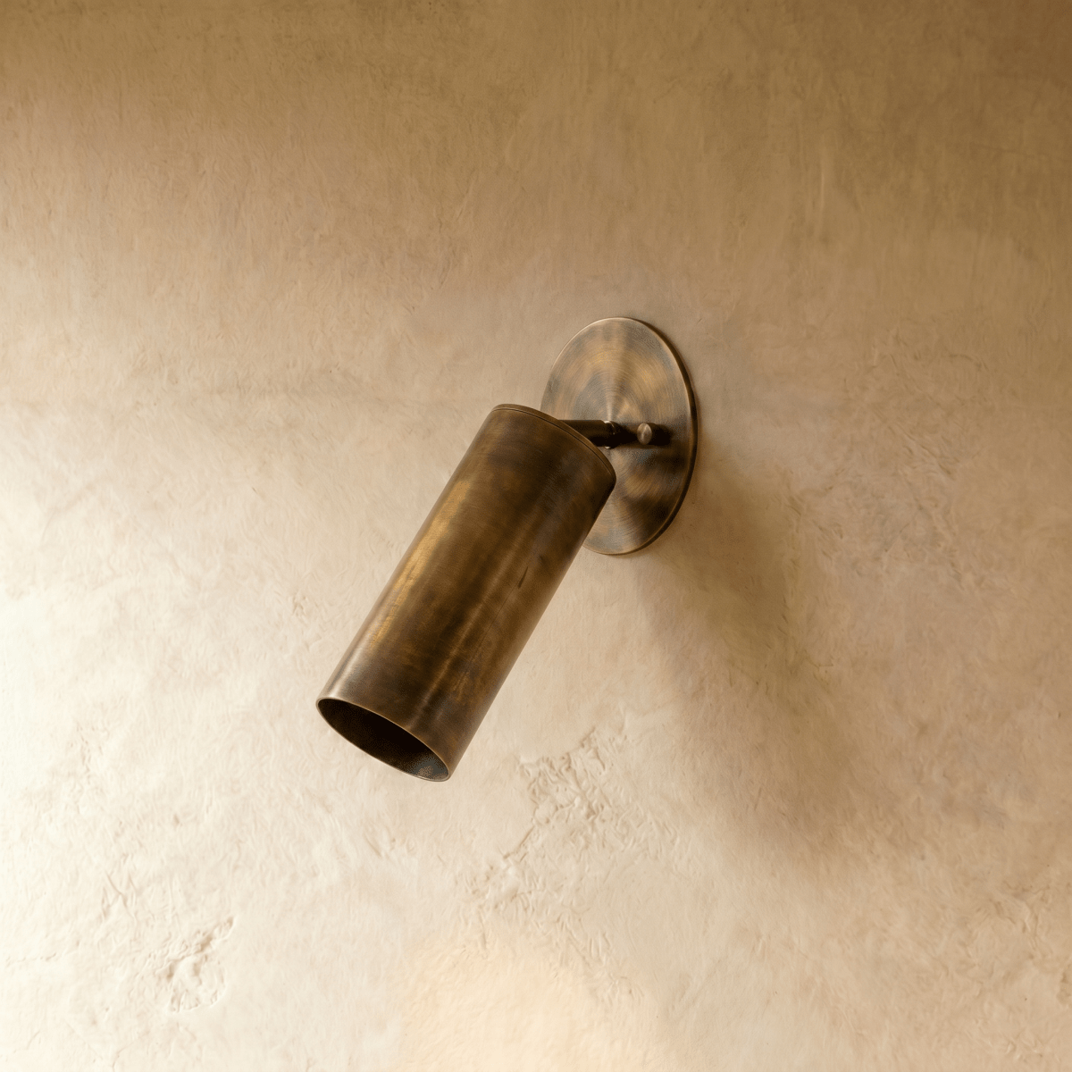 Clérachic wall lamp in vintage brass, close view of the tilted cylinder shade and oval wall plate.
