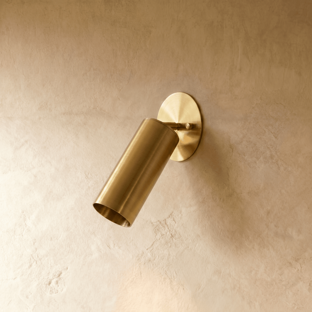 Clérachic wall lamp in satin brass, close view of the tilted cylinder shade and round wall plate.