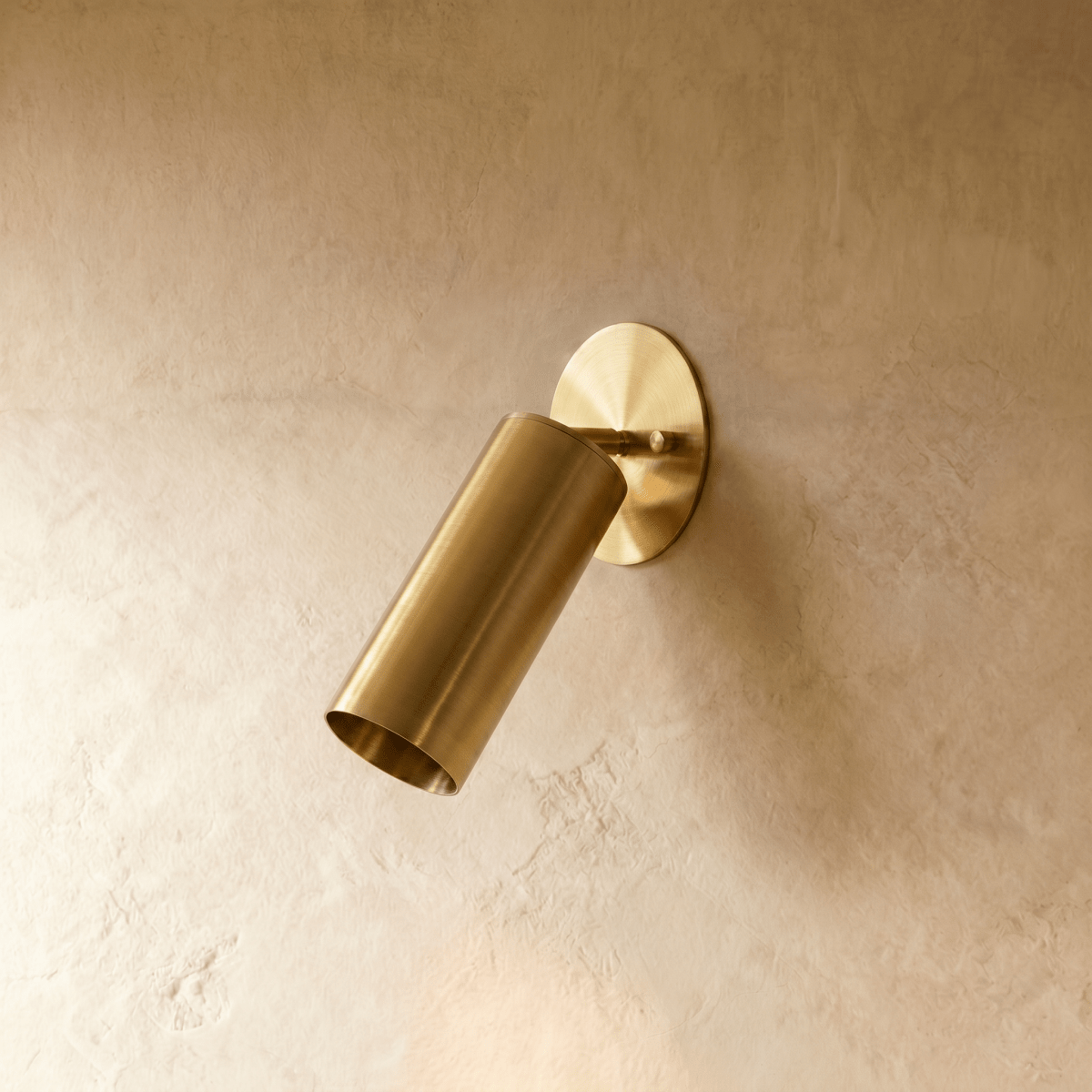 Clérachic wall lamp in satin brass, close view of the tilted cylinder shade and round wall plate.