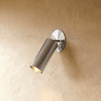 Clérachic wall lamp in chrome, an adjustable cylinder spotlight angled down from an oval wall plate.