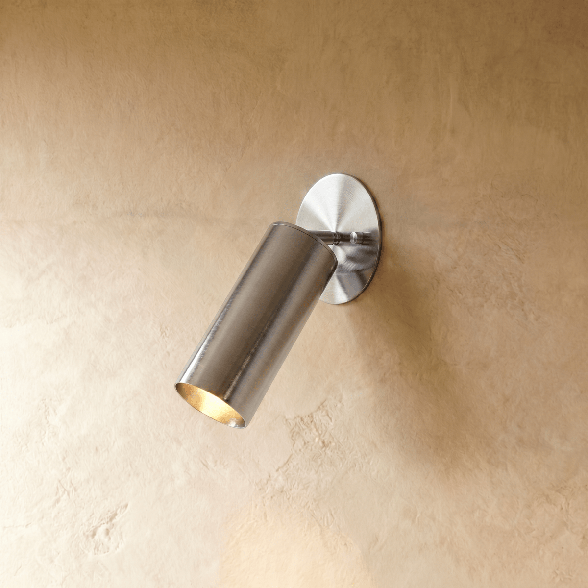 Clérachic wall lamp in chrome, an adjustable cylinder spotlight angled down from an oval wall plate.