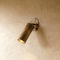 Clérachic wall lamp in vintage brass, an adjustable cylinder spotlight angled down from an oval plate.