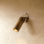 Clérachic wall lamp in vintage brass, an adjustable cylinder spotlight angled down from an oval plate.