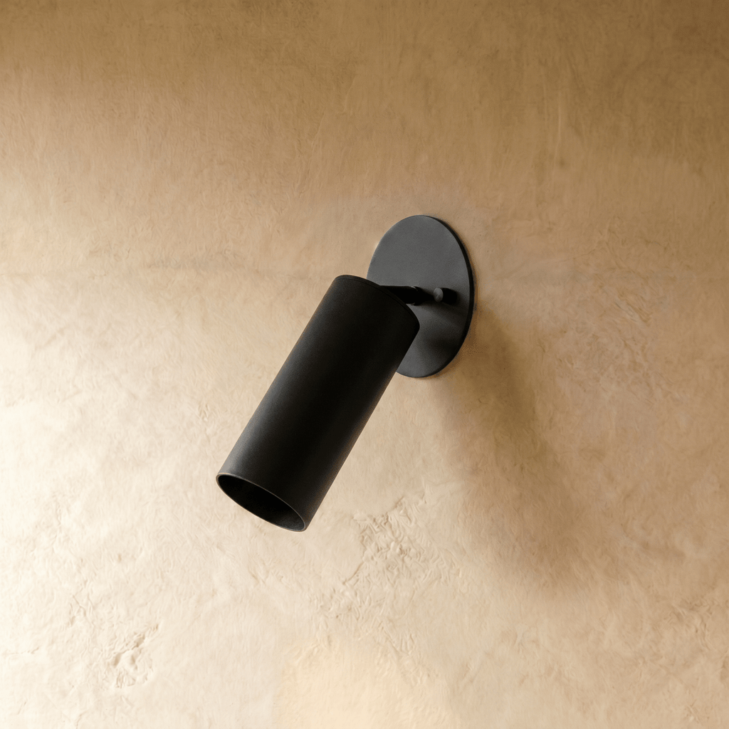 Clérachic wall lamp in matte black, close view of the tilted cylinder shade and oval wall plate.