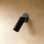 Clérachic wall lamp in matte black, close view of the tilted cylinder shade and oval wall plate.