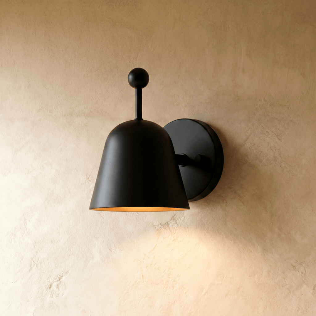 Clérachic wall lamp in matte black, its bell-shaped shade tilted forward on a round wall plate.